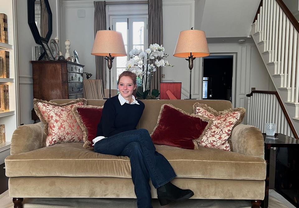 Teale Burrell wearing jeans and a sweater sitting on a couch at her home in West London.