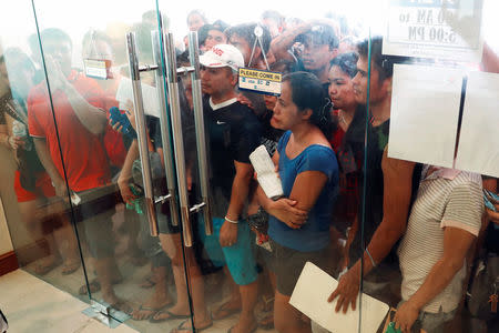 Workers who are cut off from their jobs due to the temporary closure of the holiday island Boracay, wait behind a glass door to avail transportation money from the Department of Social Welfare agency, in the Philippines April 25, 2018. REUTERS/Erik De Castro