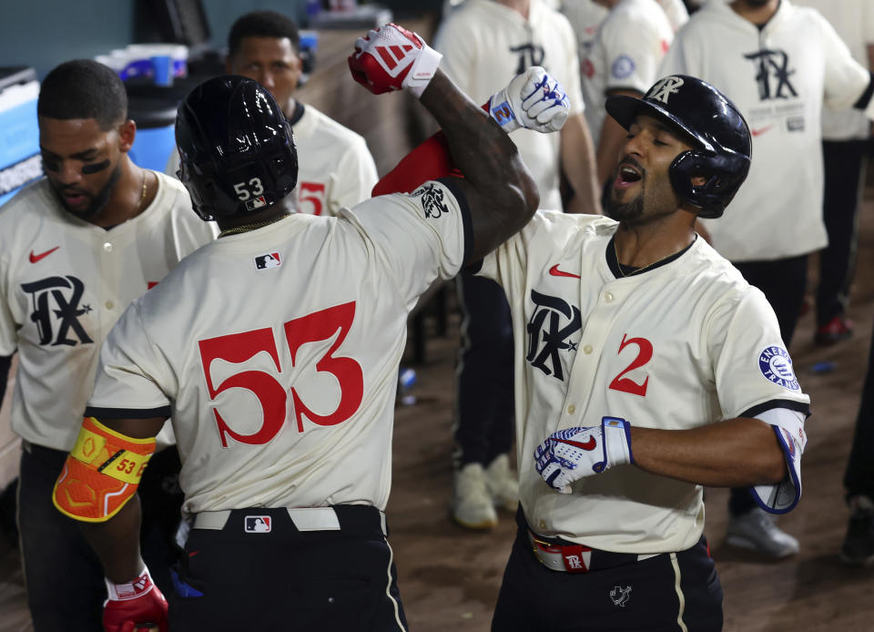 Texas Rangers' Adolis García (53) celebrates the home run by Marcus Semien (2) against the Cincinnati Reds during the eighth inning of a baseball game Friday, April 26, 2024, in Arlington, Texas. (AP Photo/Richard W. Rodriguez)