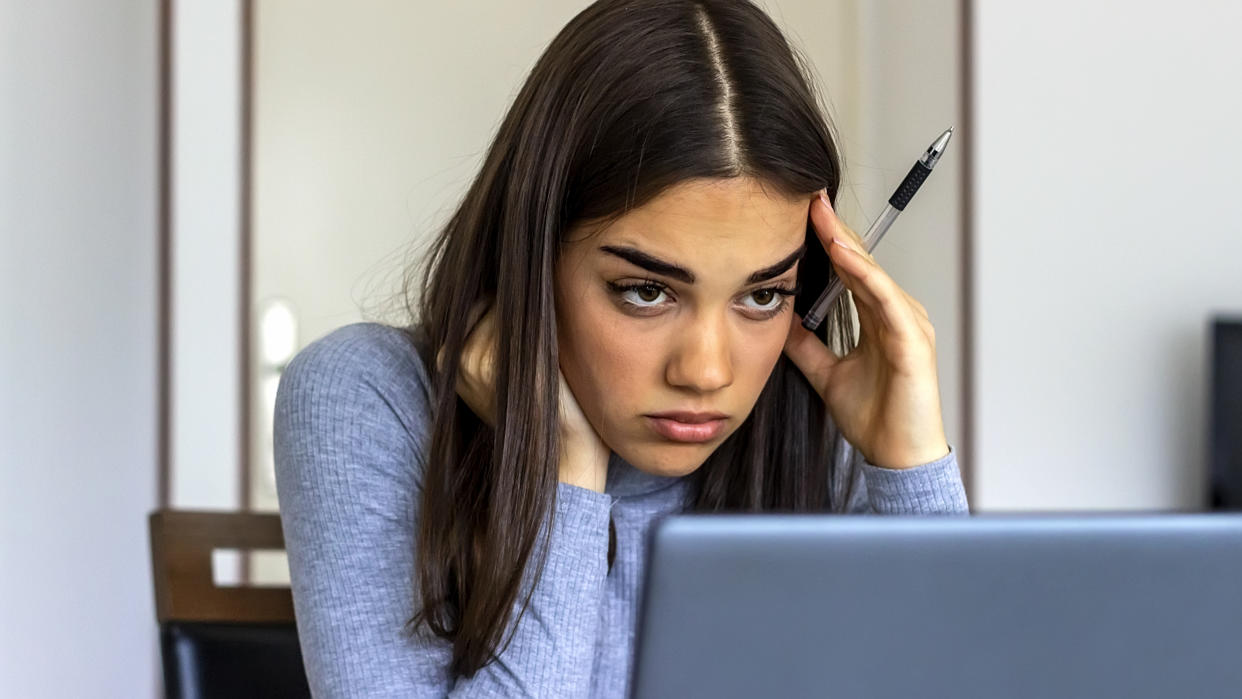 Serious young business woman with a worried expression sitting reading information on her laptop. Shot of a young business woman looking stressed and concerned while using a laptop in her home office.