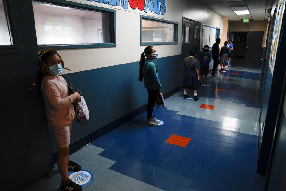 FILE - In this Aug. 26, 2020, file photo, Los Angeles Unified School District students stand in a hallway socially distance during a lunch break at Boys & Girls Club of Hollywood in Los Angeles. An effort to reopen schools in California is foundering, stoking the frustration of parents and the governor of America's biggest and wealthiest state. As the one-year anniversary of distance learning approaches, parents are grappling more than ever with the toll of isolation and intense screen time on their kids well-being. (AP Photo/Jae C. Hong, File)