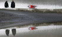 Course workers look at Switzerland's Martina Koch speeding down the track during the women's luge World Cup at the "Sanki" sliding center in the winter sport resort of Rosa Khutor, a venue for the Sochi 2014 Winter Olympics near Sochi February 22, 2013. Although many complexes and venues in the Black Sea resort of Sochi mostly resemble building sites that are still under construction, there is nothing to suggest any concern over readiness. Construction will be completed by August 2013 according to organizers. The Sochi 2014 Winter Olympics opens on February 7, 2014. REUTERS/Kai Pfaffenbach (RUSSIA - Tags: SPORT OLYMPICS) - RTR3E44C