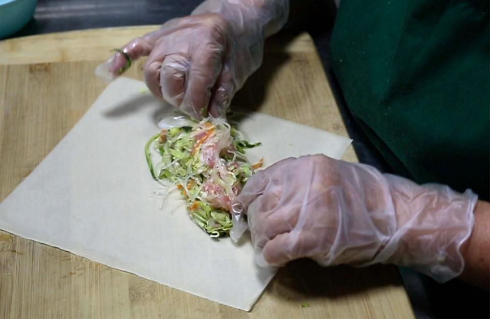 Union Asian Market’s May Yer Xiong, of Sheboygan, places the inside mixture of an Hmong egg roll in Sheboygan.