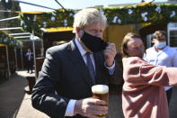 Britain's Prime Minister Boris Johnson removes his mask in the beer garden during a visit to The Mount pub and restaurant in Wolverhampton, central England, Monday April 19, 2021, during the Conservative party election campaign. (Jacob King/Pool via AP)