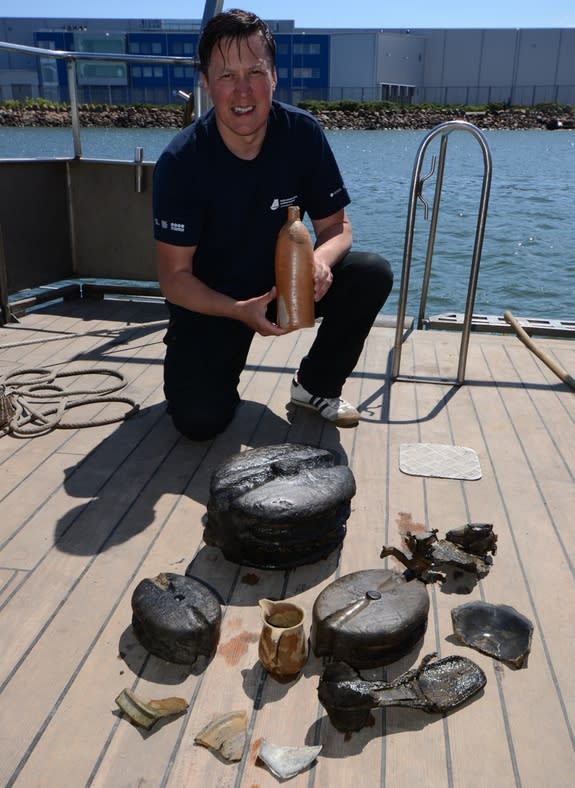 Tomasz Bednarz, an underwater archaeologist the National Maritime Museum, holds the 200-year-old Selters bottle with other shipwreck finds in front of him.