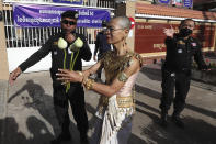 Theary Seng, a Cambodian-American lawyer, dressed in a traditional Khmer Apsara dance costume, holds lotus flowers as she arrives to continue her trial in the municipal court in Phnom Penh, Cambodia, Tuesday, Dec. 7, 2021. Seng and over 40 other defendants charged with treason for taking part in nonviolent political activities were summoned back to court Tuesday to continue their trial that had been suspended since November 2020 due to the coronavirus. (AP Photo/Heng Sinith)