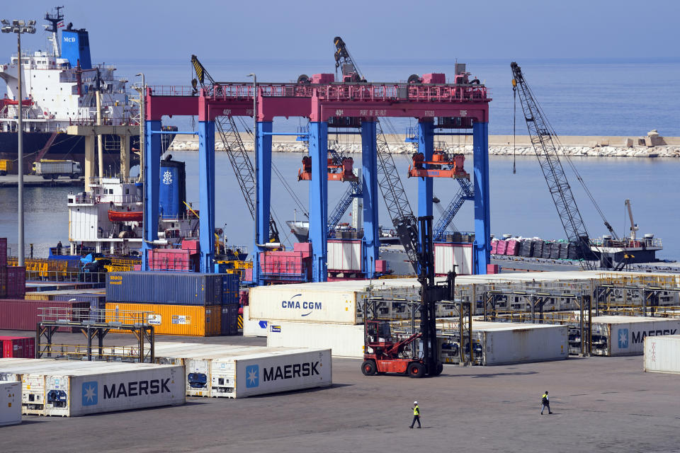 Workers walk past gantry cranes at the Beirut Port, in Beirut, Lebanon, Wednesday, March 13, 2024. Three and a half years after hundreds of tons of improperly stored ammonium nitrate ignited at the Beirut port, setting off one of the world's biggest non-nuclear explosions, Lebanese and French officials put forward a plan for reconstruction and reorganization of the port Wednesday. (AP Photo/Bilal Hussein)