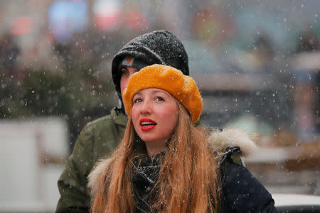 A woman looks up as snow falls in the Times Square neighborhood of New York, U.S., February 12, 2019. REUTERS/Lucas Jackson