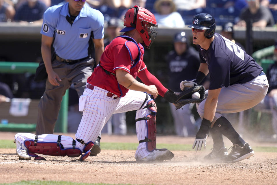 Philadelphia Phillies catcher Donny Sands, left, tags New York Yankees' DJ LeMahieu out at the plate during the fifth inning of a spring training baseball game, Friday, March 25, 2022, in Clearwater, Fla. (AP Photo/Lynne Sladky)