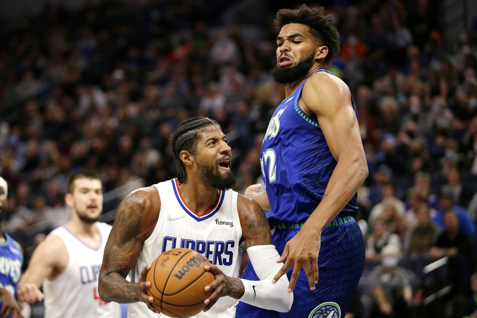 Los Angeles Clippers guard Paul George, left, drives on Minnesota Timberwolves center Karl-Anthony Towns during the first half of an NBA basketball game Friday, Nov. 5, 2021, in Minneapolis. (AP Photo/Andy Clayton-King)