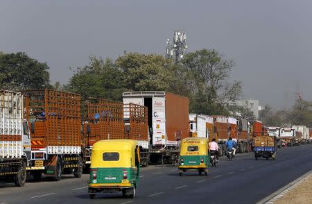 Auto rickshaws move past parked trucks along a national highway on the outskirts of Ahmedabad, India, December 2, 2015. REUTERS/Amit Dave