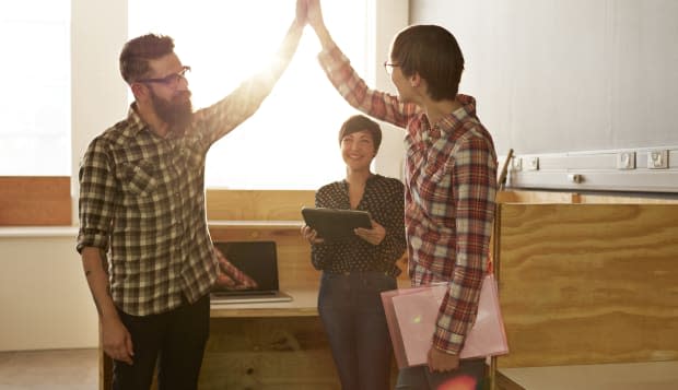 Creative coworkers doing high five at office