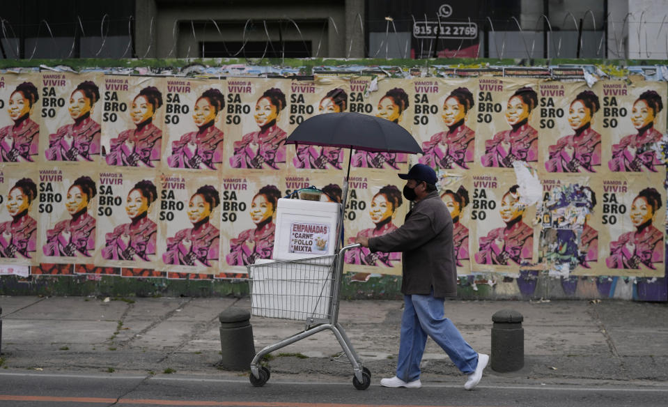 Un vendedor de empanadas empuja su carrito frente a los carteles de campaña de Francia Márquez, compañera de fórmula del candidato presidencial Gustavo Petro, de la coalición Pacto Histórico, en Bogotá, Colombia, el viernes 17 de junio de 2022. (Foto AP/Fernando Vergara)