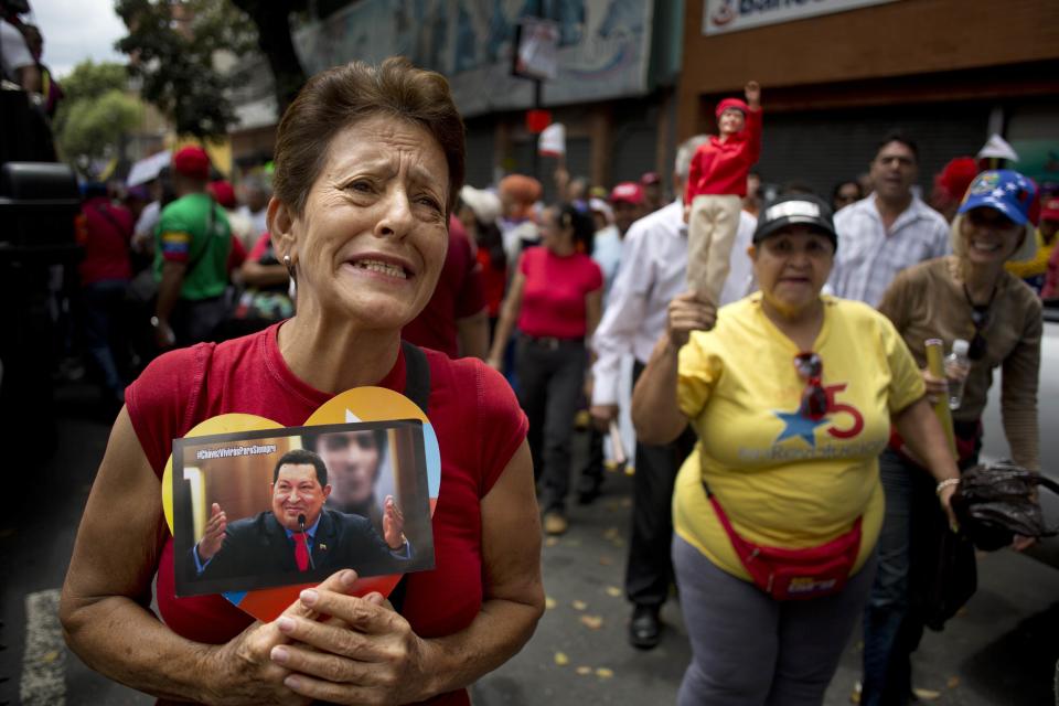 A woman chants pro-government slogans and holds a heart-framed photograph of Venezuela's late President Hugo Chavez at a rally attended by elderly people in Caracas, Venezuela, Sunday, Feb. 23, 2014. The march for peace was organized by the government and ended at Miraflores presidential palace where the marchers met with Venezuela's President Nicolas Maduro. (AP Photo/Rodrigo Abd)