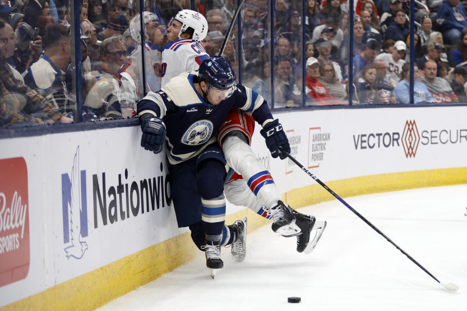 Columbus Blue Jackets defenseman David Jiricek (55) reaches for the puck in front of New York Rangers forward Will Cuylle, top, during the first period of an NHL hockey game in Columbus, Ohio, Saturday, Oct. 14, 2023. (AP Photo/Paul Vernon)