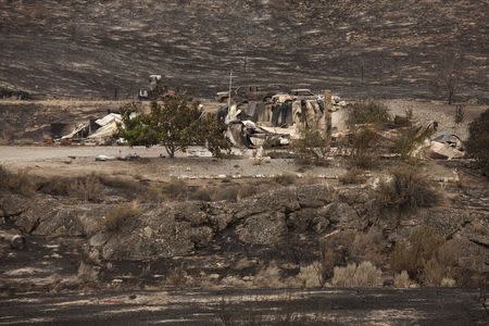 Damaged structures and cars sit smouldering after being consumed by the Carlton Complex fire near Pateros, Washington July 19, 2014. REUTERS/David Ryder