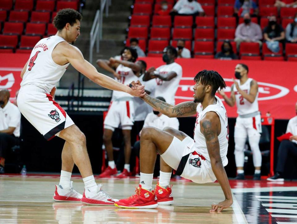 N.C. State’s Jericole Hellems (4) helps up Manny Bates (15) during the first half of N.C. State’s game against Pittsburgh at PNC Arena in Raleigh, N.C., Sunday, February 28, 2021.