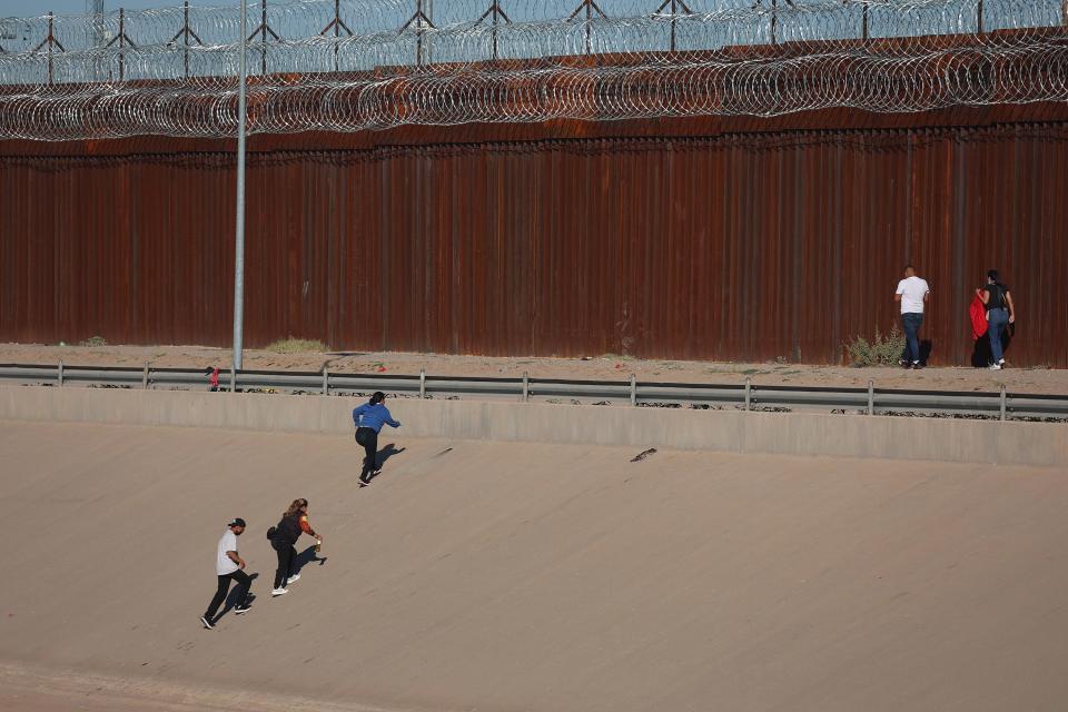 Migrants walk along the U.S. Border fence after crossing the Rio Grande from Mexico to turn themselves in to the U.S. Border Patrol on September 22, 2022 in El Paso, Texas.