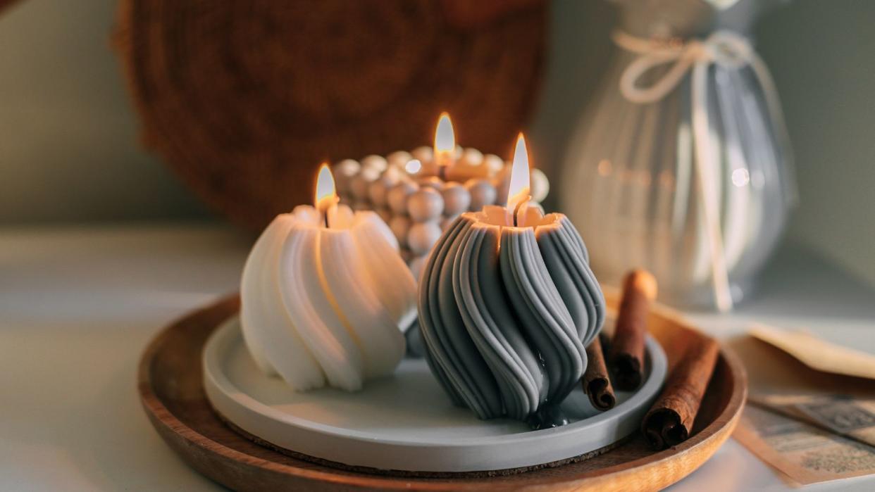  Three sculpted candles with swirl pattern exteriors lit on a tray 