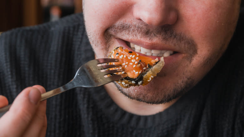 man eats salmon with fork