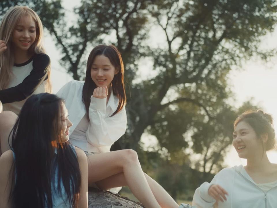 the four members of aespa sitting together and laughing outside