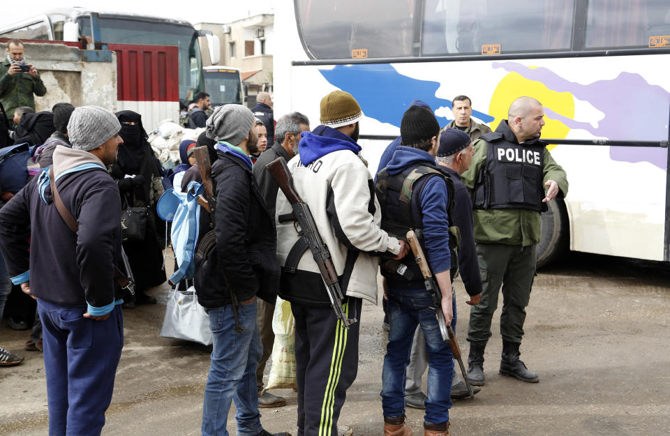 Gunmen carrying their weapons and family members leave the al-Waer neighborhood bound for a town on the Turkish border, in Homs, Syria, Saturday, March 18, 2017. Scores of Syrian opposition fighters and their families have begun leaving al-Waer, the last rebel-held neighborhood in the central city of Homs, as part of a Russian-backed evacuation deal signed earlier this week. The city was once known as the epicenter of the 2011 uprising against President Bashar Assad. (AP Photo)