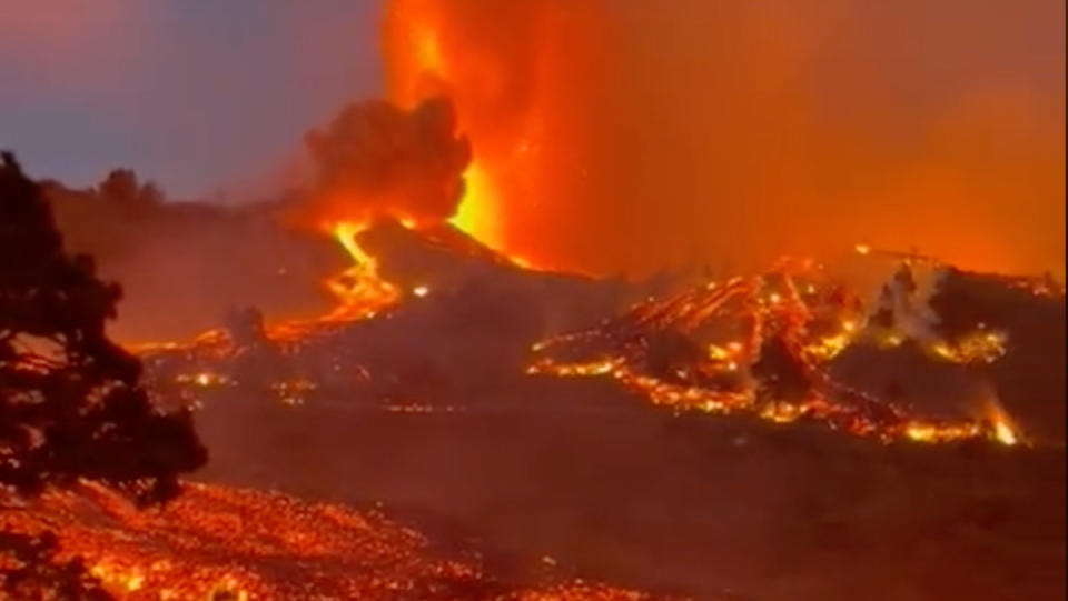 A forested mountain in the Canary Islands covered in oozing lava and fire.