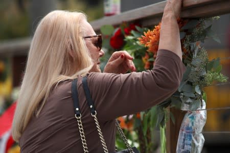 A woman places flowers at a makeshift memorial near Truth Aquatics as the search continues for those missing in a pre-dawn fire that sank a commercial diving boat near Santa Barbara, California