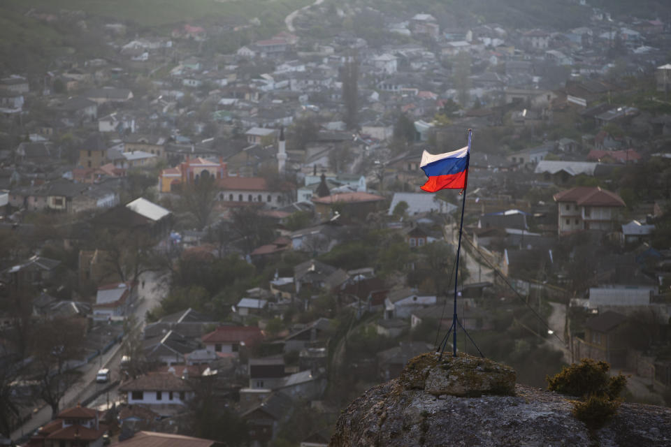 FILE - In this March 28, 2014 file photo, a Russian national flag flies on a hilltop near the city of Bakhchysarai, Crimea. The European Court of Human Rights decided Thursday Jan. 14, 2021, to start considering Ukraine's complaint against alleged human rights violations in the Russia-annexed Crimea. (AP Photo/Pavel Golovkin, File)