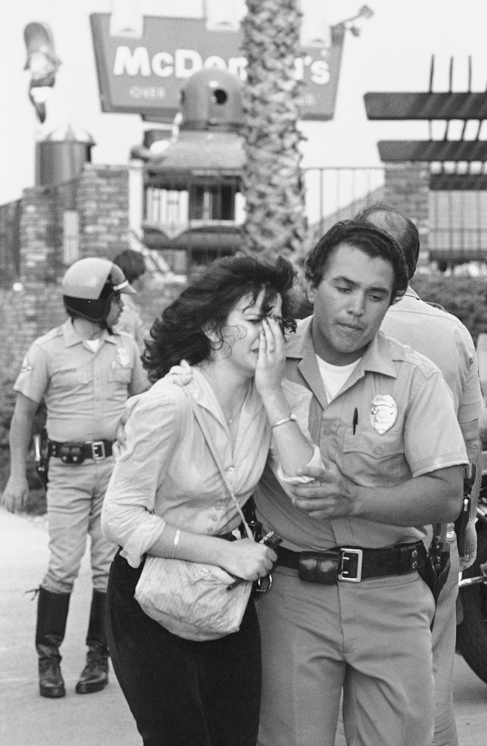 FILE - In this July 18, 1984, photo taken by Associated Press photographer Leonard Ignelzi, a bloodied victim is led away by police as SWAT officers assist the wounded at a McDonald's restaurant in San Ysidro, Calif., after a gunman killed 21 people and wounded several others. Ignelzi, whose knack for being in the right place at the right time produced breathtaking images of Hall of Fame sports figures, life along the U.S.-Mexico border, devastating wildfires and numerous other major news events over nearly four decades as a photographer for The Associated Press in San Diego, died Friday, April 29, 2022. He was 74. (AP Photo/Lenny Ignelzi, File)