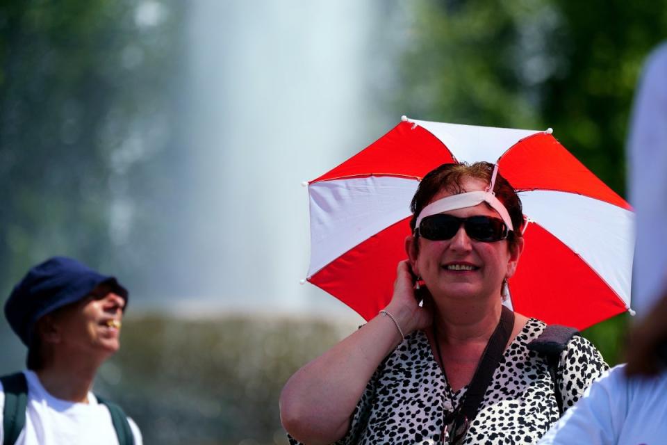 A woman wears an umbrella shield on her head during hot weather in Trafalgar Square (Victoria Jones/PA) (PA Wire)