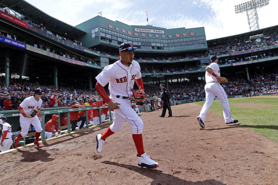 FILE - In this April 3, 2017, file photo, Boston Red Sox players including Mookie Betts, middle, take the field for the start of their baseball home opener against the Pittsburgh Pirates, at Fenway Parkin Boston. The Red Sox have fumigated and disinfected their clubhouse at Fenway Park to help fight the flu. Boston manager John Farrell says it has been done a few times while the team has been on the road. The Red Sox have been hit hard by the bug. Hanley Ramirez has played just two games because of it, and Mookie Betts returned to the lineup Sunday after the flu kept him out for almost a week. (AP Photo/Elise Amendola, File)