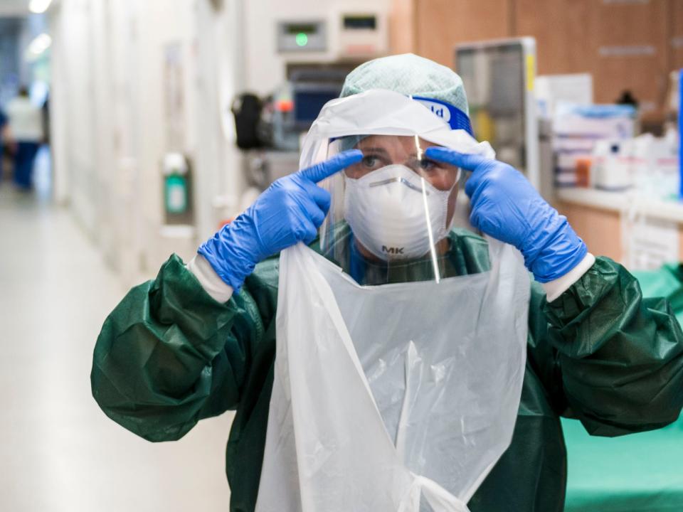 A nurse putting on protective gear.