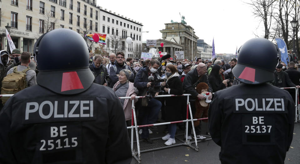 Police officers block a road between the Brandenburg Gate and the Reichstag building, home of the German federal parliament, as people attend a protest rally in front of the Brandenburg Gate in Berlin, Germany, Wednesday, Nov. 18, 2020 against the coronavirus restrictions in Germany. Police in Berlin have requested thousands of reinforcements from other parts of Germany to cope with planned protests by people opposed to coronavirus restrictions. (AP Photo/Michael Sohn)