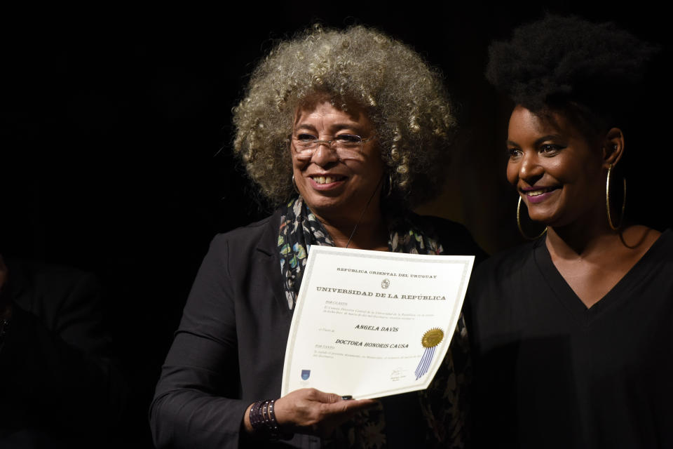 FILE- In this March 23, 2019 file photo, American political activist Angela Davis, left, receives the Honoris Causa from Noelia Ojeda, during an open air rally in front of the University of the Republic in Montevideo, Uruguay. Davis is among 10 people who will be inducted into the National Women's Hall of Fame during a ceremony on Saturday, Sept. 14, 2019. (AP Photo/Matilde Campodonico, File)