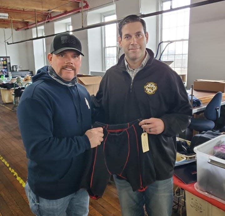 Levi Bousquet, Northampton firefighter and founder of 9 Alarm Apparel, and Fall River firefighter Jason Burns hold a pair of 9 Alarm's Defender Briefs at Precision Sportswear in Fall River.