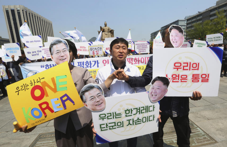FILE - In this April 25, 2018 file photo, activists with cutouts of South Korean President Moon Jae-in, left, and North Korean leader Kim Jong Un participate in a rally welcoming the planned summit between South and North Korea in Seoul, South Korea. Kim and South Korean President Moon Jae-in announced in the North Korean capital of Pyongyang this week that Kim has accepted Moon’s request to visit Seoul soon, maybe within the year. The signs read: " We Are A Nation and Our Wish Is Unification." (AP Photo/Ahn Young-joon, File)