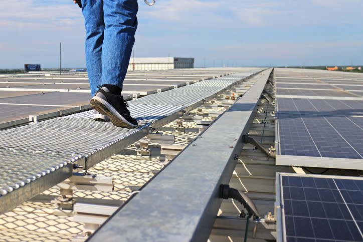 A person walking along a rooftop solar installation.
