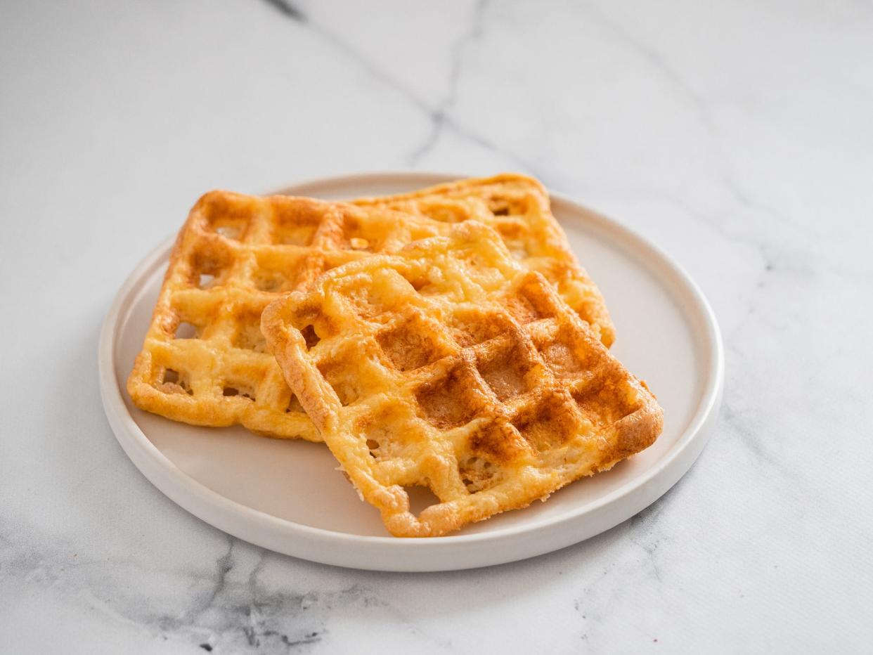 Perfect savory keto waffles. Two ingredients chaffles on plate over white marble background. Eggs and parmesan cheese low carb waffles.