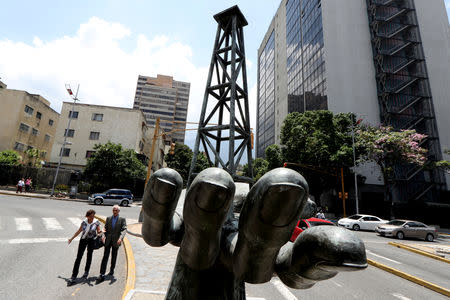 People walk past a sculpture outside a building of Venezuela's state oil company PDVSA in Caracas, Venezuela May 17, 2019. REUTERS/Ivan Alvarado