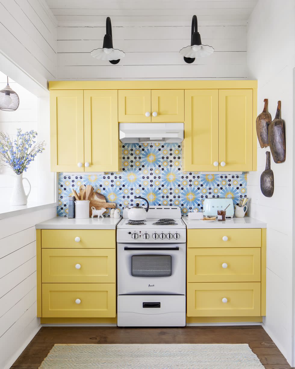 small kitchen with yellow cabinets, white shiplap walls, and blue, navy, and yellow patterned tile backsplash