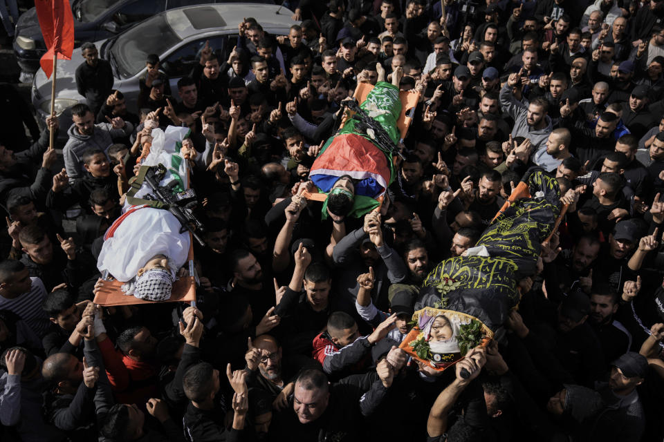 Mourners carry the bodies of Asaad Al-Dam, right, Mahmoud Abu Al-Hayja, center, and Ammar Abu Al-Wafa, draped in the Islamic Jihad militant group and Hamas flags, during their funeral in the Jenin refugee camp, West Bank, Sunday, Nov. 26, 2023. Israeli forces operating in the occupied West Bank killed at least eight Palestinians in a 24-hour period, Palestinian health officials said Sunday. (AP Photo/Majdi Mohammed)