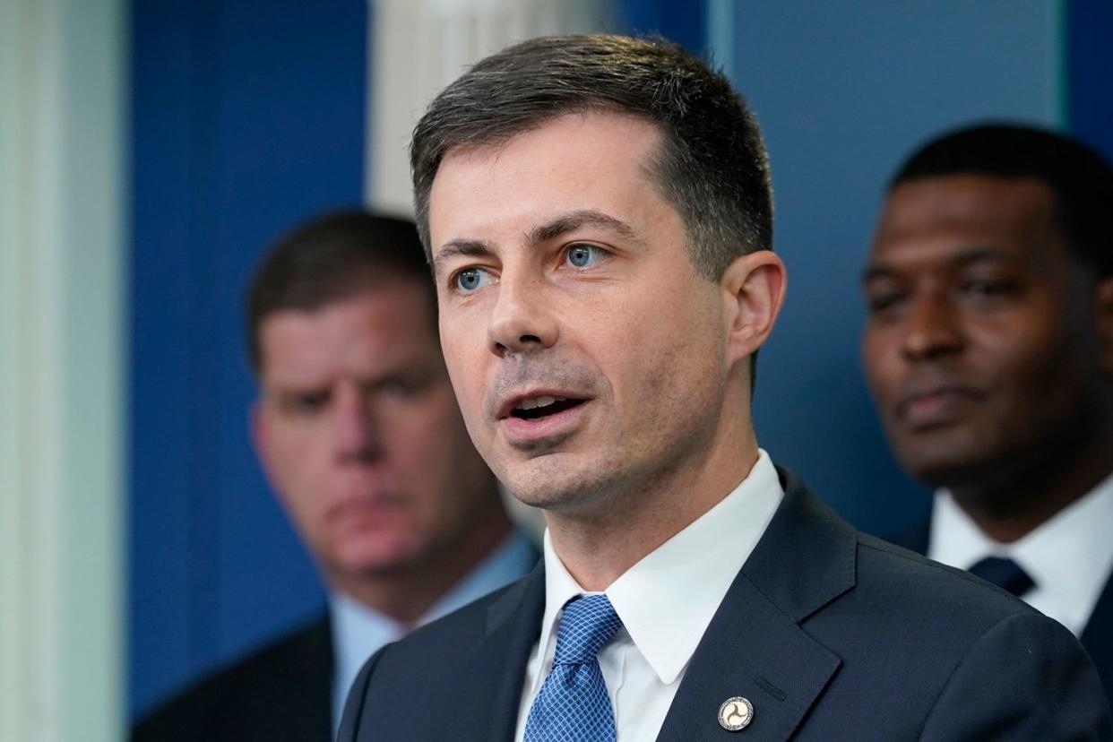 Transportation Secretary Pete Buttigieg, center, speaks during a briefing at the White House in Washington, Monday, May 16, 2022, on the six-month anniversary of the bipartisan infrastructure law. Labor Secretary Marty Walsh, left, and Environmental Protection Agency administrator Michael Regan, right, listen.