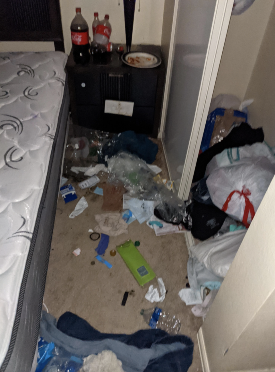 Bad roomie's room, dirty with used water bottles, soda bottles, and trash bags