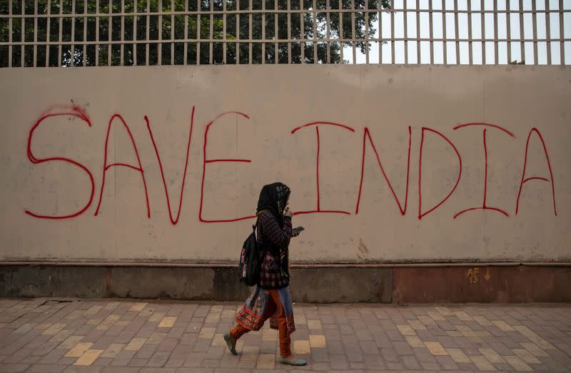 A demonstrator walks past a graffiti during a protest against a new citizenship law, outside the Jamia Millia Islamia university in New Delhi