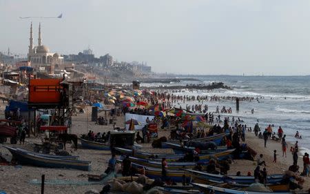 Palestinians swim to cool off in the Mediterranean Sea as others enjoy their time on a beach in the northern Gaza Strip July 13, 2018. Picture taken July 13, 2018. REUTERS/Mohammed Salem