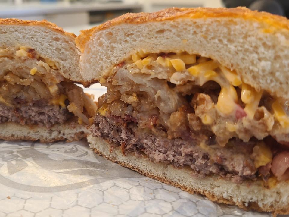 Wendy's big bacon cheddar cheeseburger cut in half and open on a white wrapper