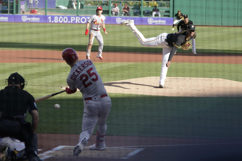 St. Louis Cardinals' Corey Dickerson (25) hits a ground ball on a pitch from Pittsburgh Pirates relief pitcher Johan Oviedo, right, that scored Tommy Edman, top, from second on an error during the first inning of a baseball game, Wednesday, Oct. 5, 2022, in Pittsburgh. (AP Photo/Keith Srakocic)