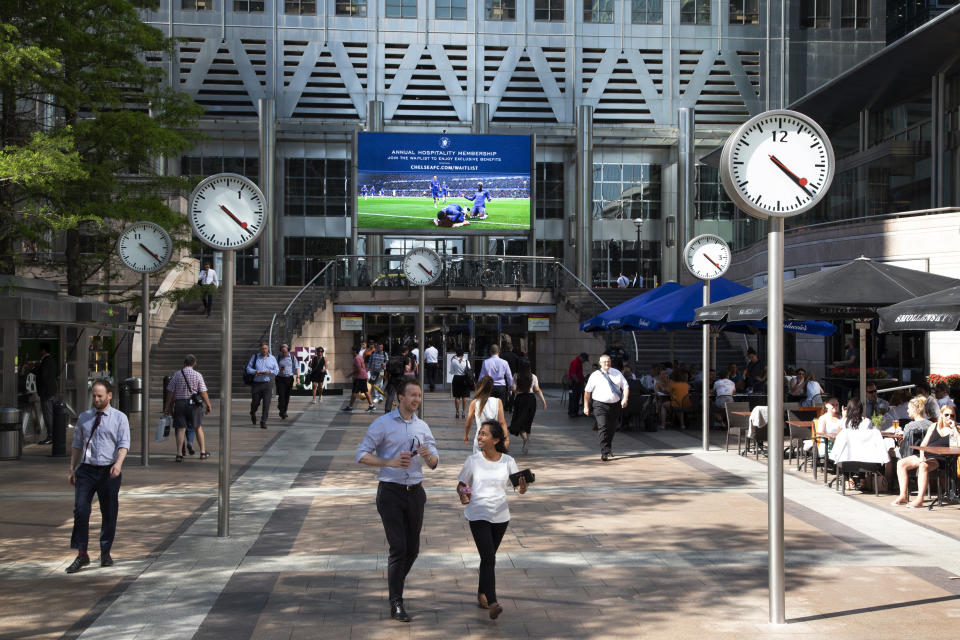 City workers walk under the clocks of Nash Court in Reuters Plaza at the base of One Canada Square in Canary Wharf financial district in London, England, United Kingdom. Canary Wharf is a financial area which is still growing as construction of new skyscrapers continues. (photo by Mike Kemp/In Pictures via Getty Images Images)