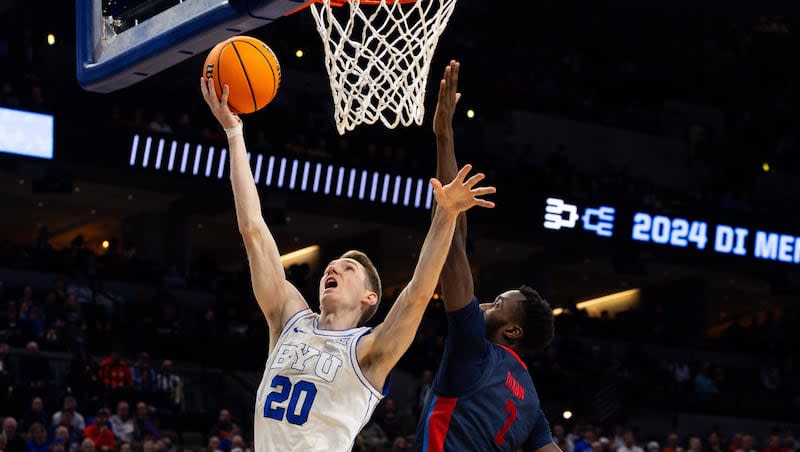 Brigham Young Cougars guard Spencer Johnson (20) shoots the ball with Duquesne Dukes forward David Dixon (2) on defense during the game between the Brigham Young Cougars and the Duquesne Dukes in the first round of the 2024 NCAA Tournament at the CHI Health Center in Omaha on Thursday, March 21, 2024.